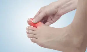 Dłoń uciska palce u stopy, zaznaczone czerwonym bólem.