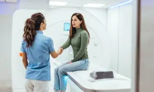 Pacjentka i technik medyczny uśmiechają się do siebie przed aparatem do rezonansu magnetycznego, pokazując, jak wygląda rezonans magnetyczny.