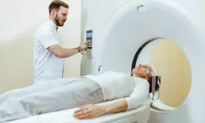 Pacjentka leży na stole tomografu, a technik przygotowuje badanie. Po tomografii z kontrastem można jeść, ale warto skonsultować się z lekarzem.