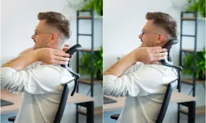 Mężczyzna w okularach siedzi przy biurku i masuje kark.