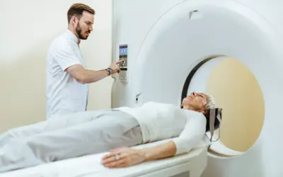 Pacjentka leży na stole tomografu, a technik przygotowuje badanie. Po tomografii z kontrastem można jeść, ale warto skonsultować się z lekarzem.