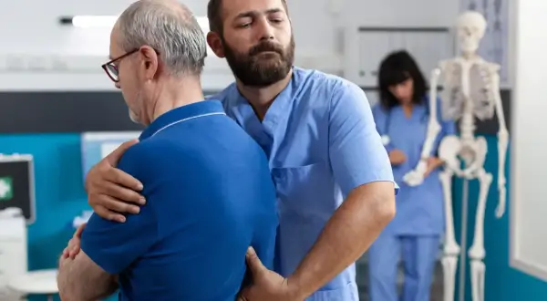 Fizjoterapeuta pomaga pacjentowi z bólem pleców w nocy i nad ranem.
