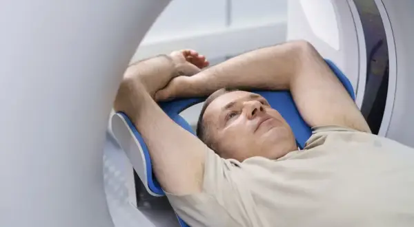 Mężczyzna leży w aparacie rezonansu magnetycznego. Czy przed rezonansem można jeść? Zależy od badania.