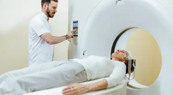 Pacjentka leży na stole tomografu, a technik przygotowuje badanie. Po tomografii z kontrastem można jeść, ale warto skonsultować się z lekarzem.