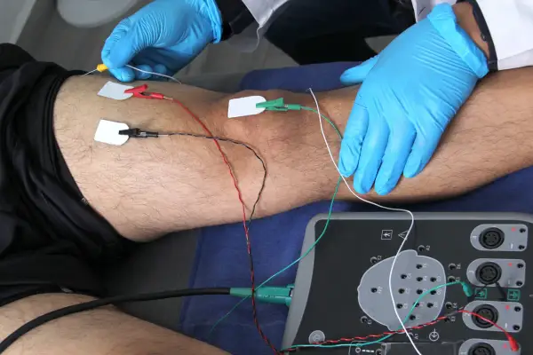 Elektrody podłączone do nogi pacjenta i aparat do badań.