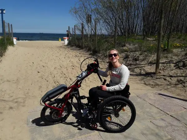 Kobieta na wózku inwalidzkim z napędem elektrycznym na plaży.