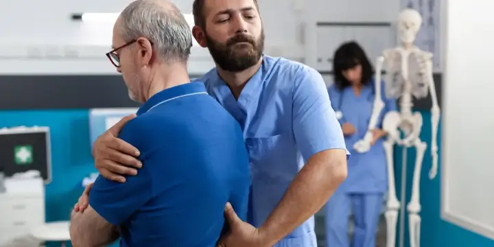 Fizjoterapeuta pomaga pacjentowi z bólem pleców w nocy i nad ranem.